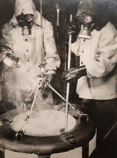 Twee werknemers in volle uitrusting inspecteren de nitreercentrifuge van Gevaert (Collectie FOMU)